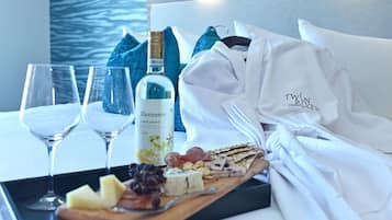 A tray with wine glasses, a bottle of wine, cheese, and snacks on a table with a white towel and a robe.