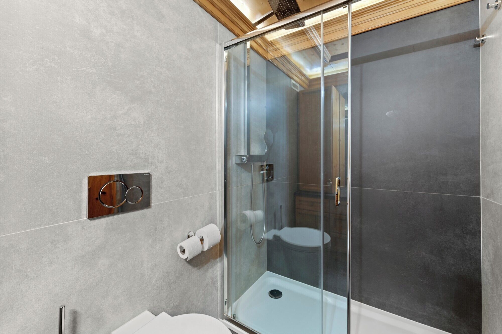 A modern bathroom with a glass-enclosed shower, a toilet, and a towel rack.