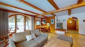 A cozy living room with a sofa, wooden dining table, and a bench. - 5½-roomed apartment on the ground floor, 140m2. (Celerina/Schlarigna)