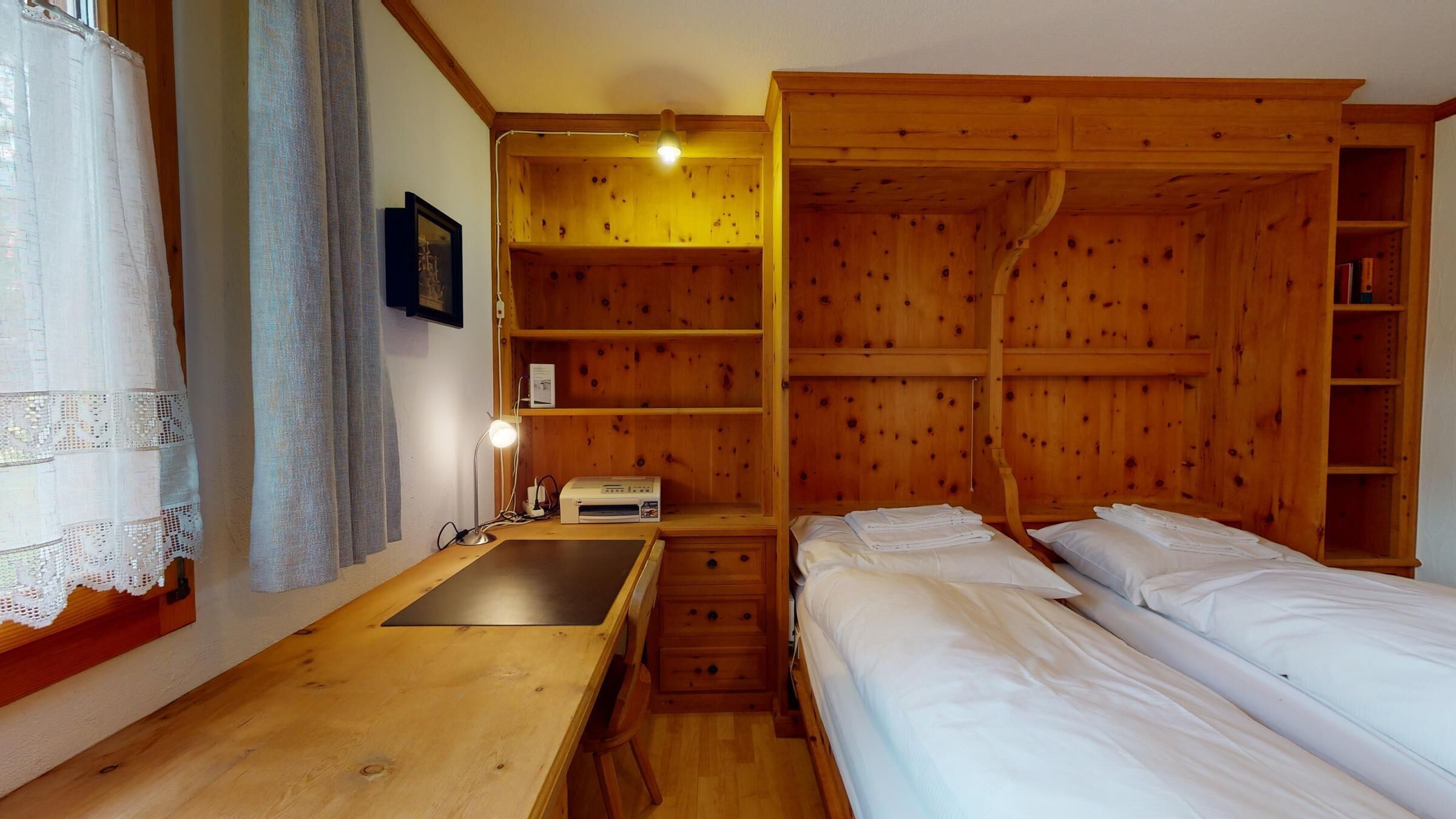 A wooden room with a bed, a desk, and a wardrobe.