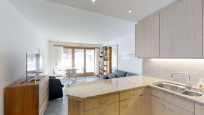 A modern kitchen with wooden cabinets, a granite countertop, and a built-in sink. - 3-room apartment on the ground floor. (Silvaplana)