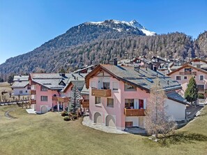 Un conjunto de edificios tradicionales de estilo chalé con techos inclinados, con una montaña nevada al fondo.