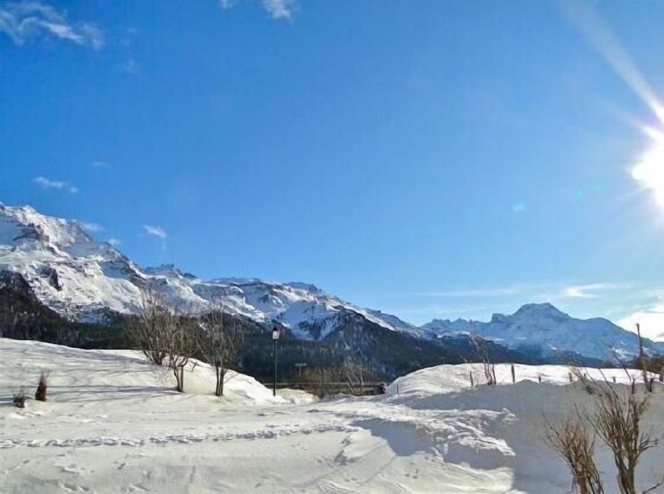 Paesaggio montano innevato con cielo sereno.