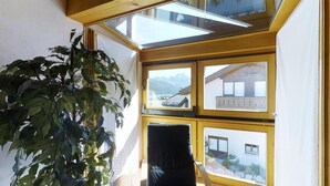 Ein Zimmer mit Dachfenster, einem Blumentopf und Blick auf einen Berg sowie ein Gebäude.