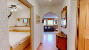 Un pasillo que conduce a una sala de estar con sofá, muebles de madera y un espejo.