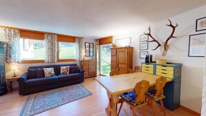 Una sala acogedora con un sofá, una mesa de comedor de madera, sillas y una alfombra.