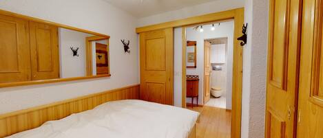 Ein Schlafzimmer mit Bett, Holzschrank und angrenzendem Badezimmer.