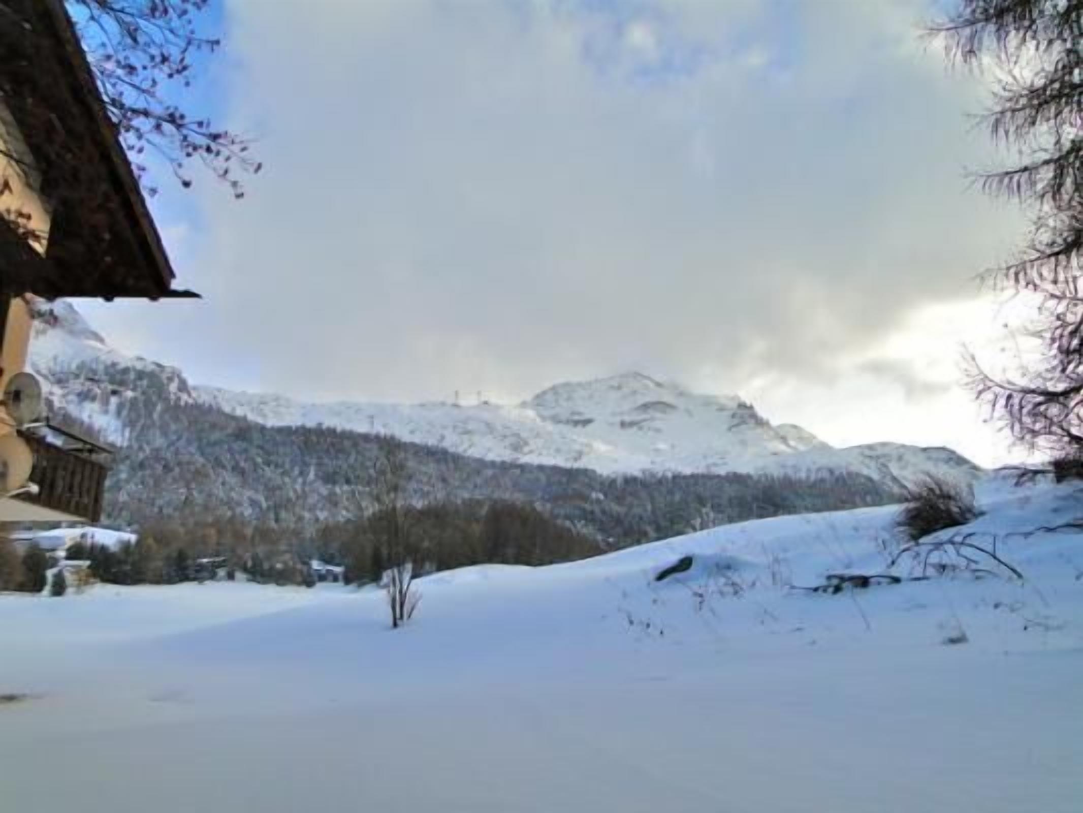 Paisagem montanhosa coberta de neve com uma cabana de madeira.