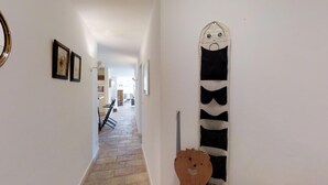 A hallway with a stone floor, a wooden door with a bear cutout, and framed pictures on the wall. - 3 ½ -room apartment on the ground floor ca. (Silvaplana-Surlej)