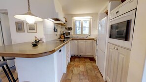 A kitchen with white cabinets, a large island, a microwave, and a window.