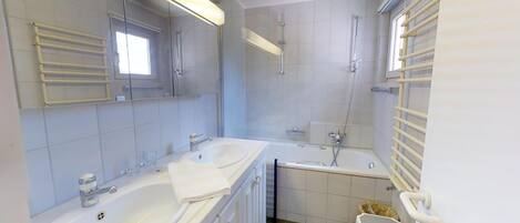 A modern bathroom with two sinks, a bathtub, and a shower.