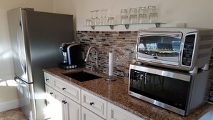 Una cucina con un frigorifero in acciaio inossidabile, un forno a microonde e una macchina da caffè sul bancone.