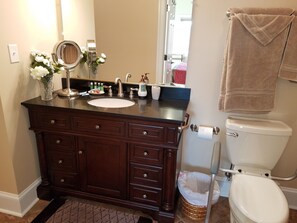 A bathroom with a dark wooden vanity, a white sink, a mirror, and a toilet. - Find out why this property is Almost Heaven (Swoope)