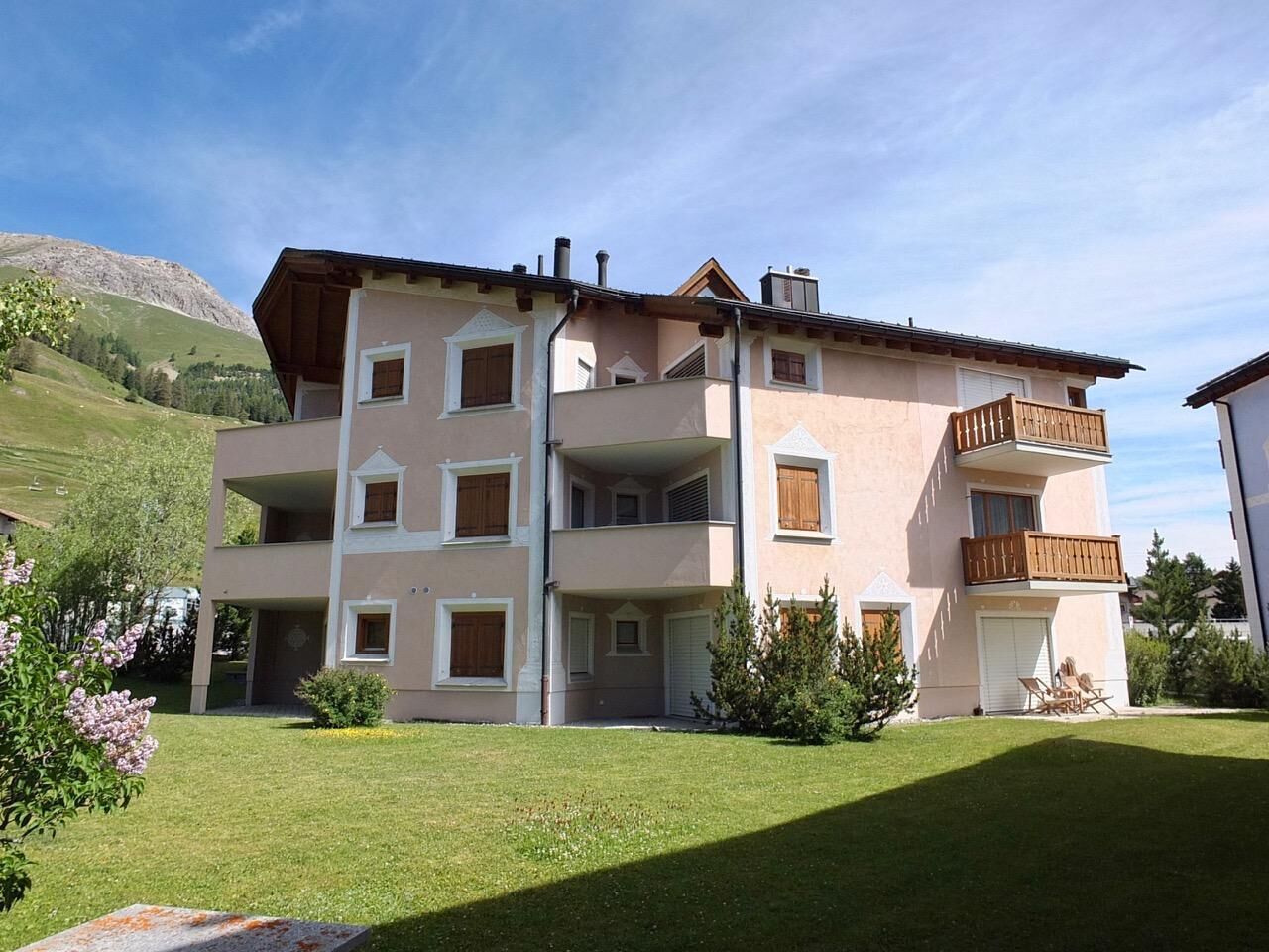 Un immeuble à plusieurs étages doté de balcons, d’un toit plat et d’une pelouse devant.