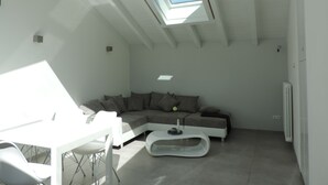 Uma sala de estar moderna com um claraboia, um sofá modular e uma mesa de centro branca.