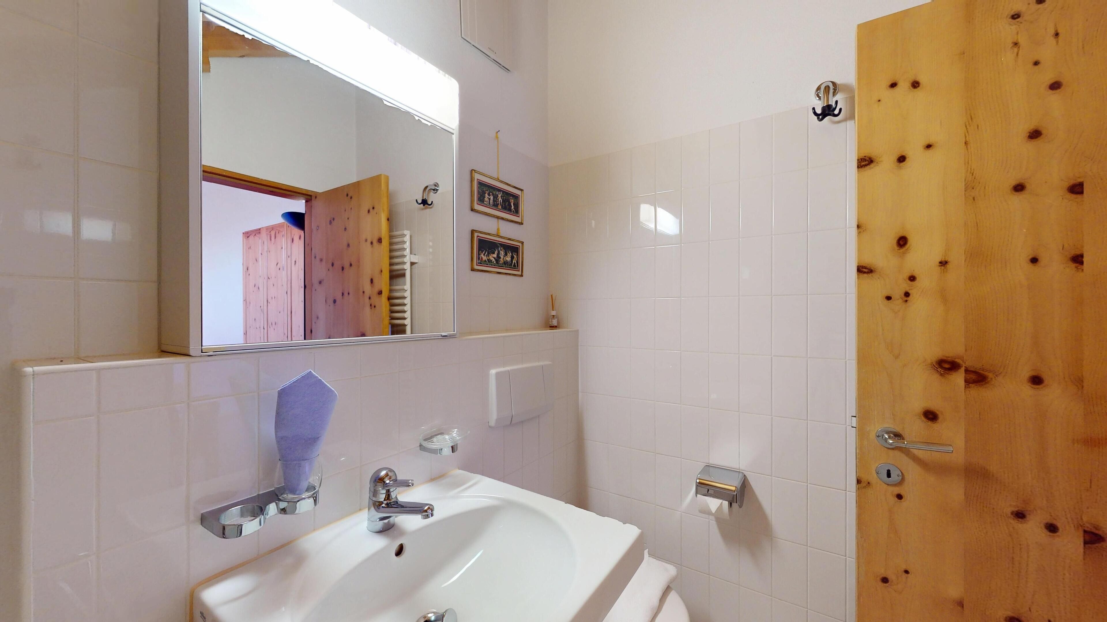 A bathroom with a white sink, mirror, and wooden door.