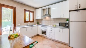 A modern kitchen with white cabinets, a stainless steel range hood, a microwave, and a refrigerator. - Casa Delicias pool near the beach in Alcudia (Alcúdia)