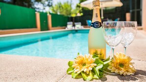 A poolside setting with a champagne bottle, two glasses, and decorative flowers. - Casa Delicias pool near the beach in Alcudia (Alcúdia)