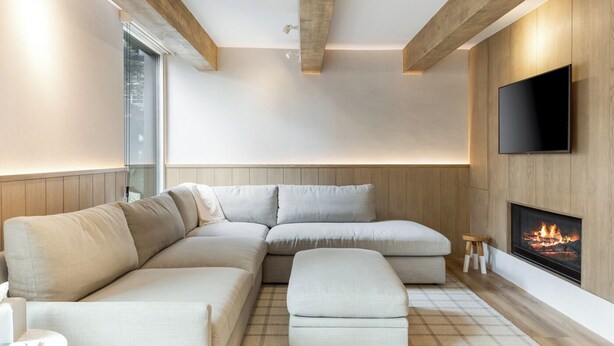 A modern living room with a sectional sofa, a flat-screen TV, and a fireplace.