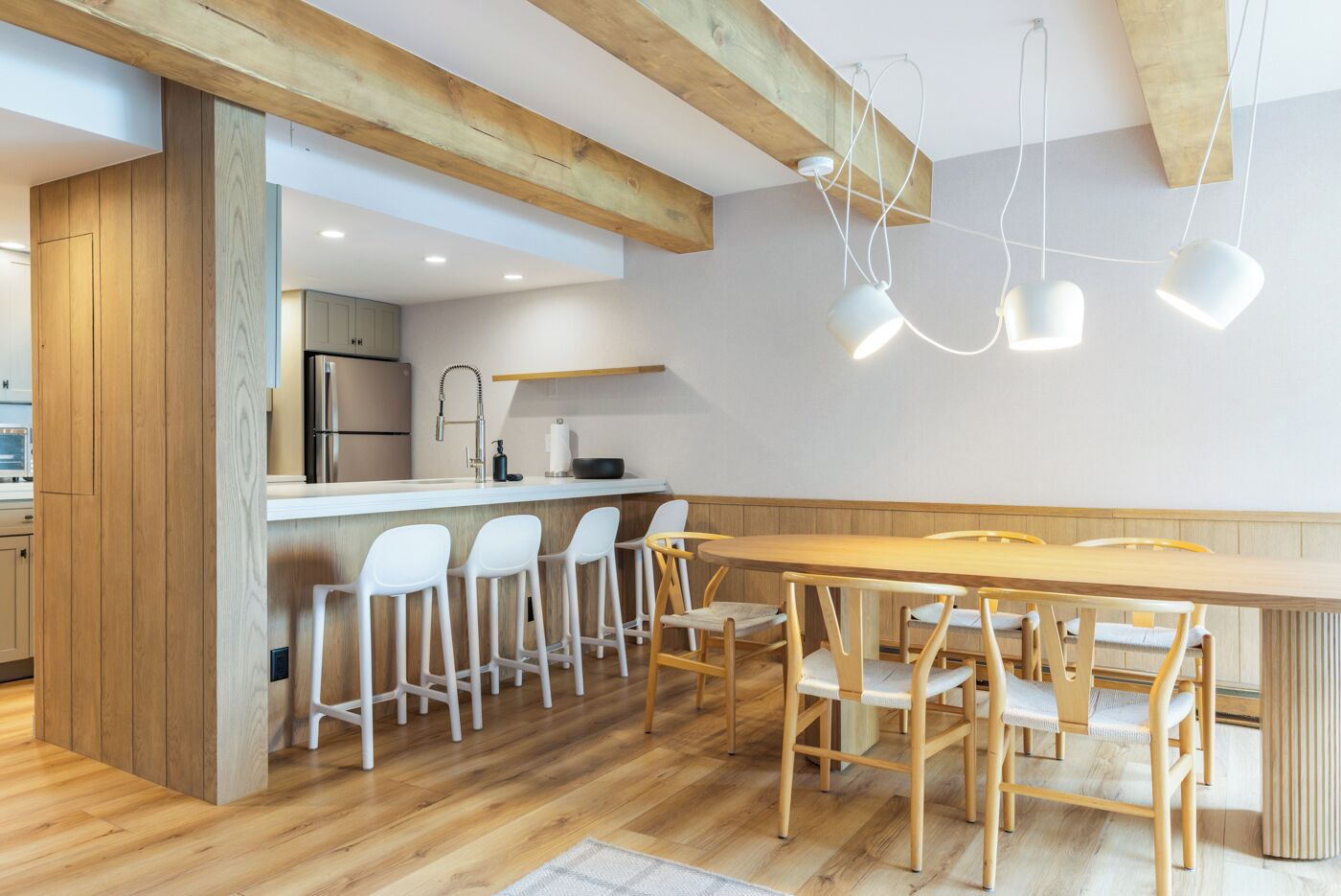 Una cucina moderna con travi in legno, un'isola centrale con sgabelli da bar e illuminazione a sospensione.