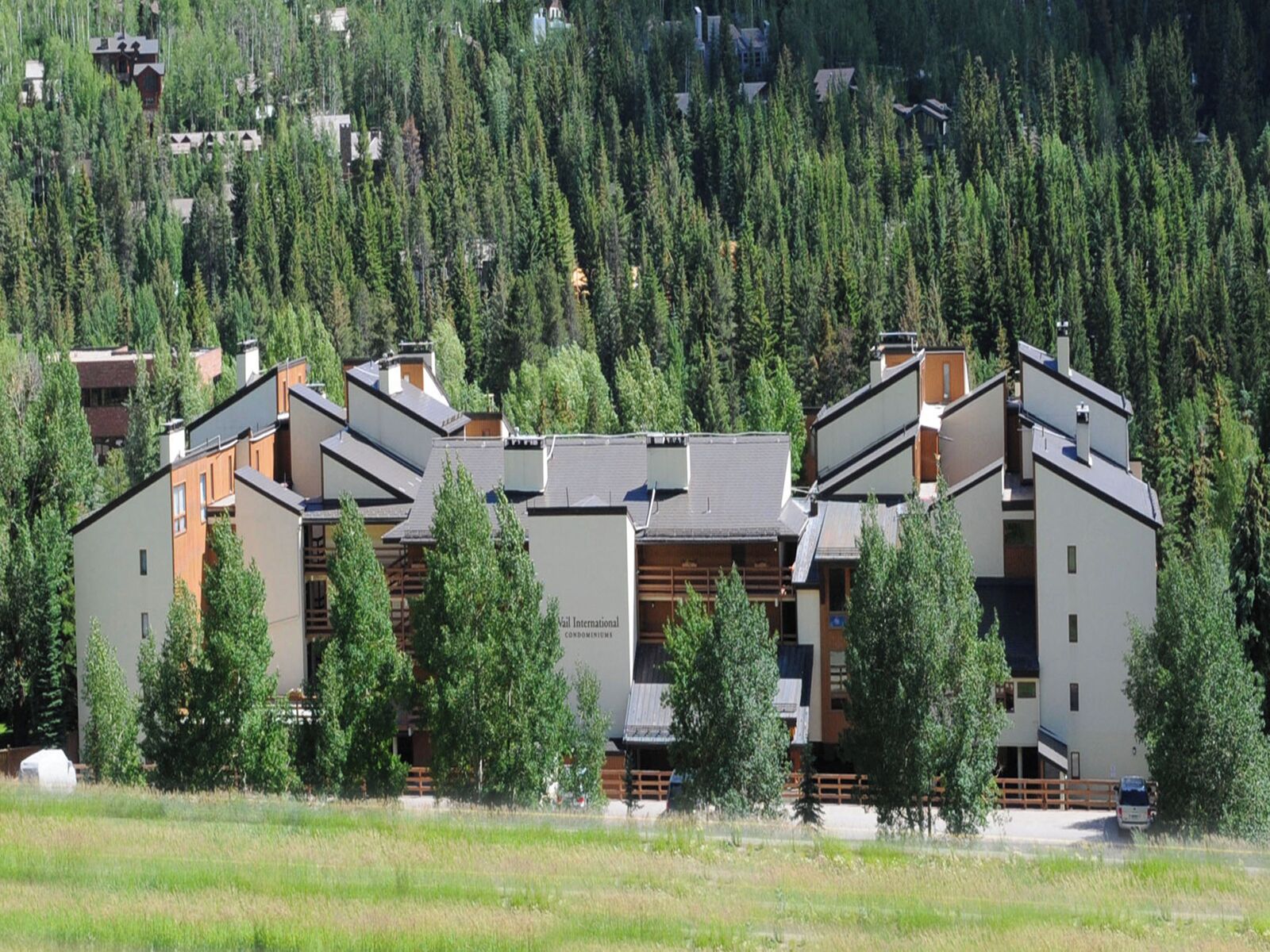 Ein modernes Hotel mit mehreren Gebäuden, umgeben von dichtem Wald und einer grünen Wiese.