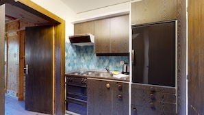 A compact kitchen with dark wood cabinets, a stainless steel sink, and a black refrigerator.
