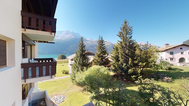 A balcony with a view of a mountain lake and surrounding trees.