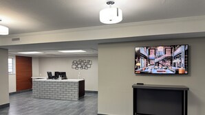 A modern reception area with a reception desk, a flat-screen TV, and a decorative wall piece. - Quality Inn Carlin (Carlin)
