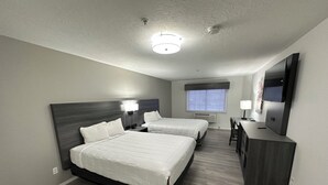 A hotel room with two beds, a desk, a chair, a TV, and a window. - Quality Inn Carlin (Carlin)