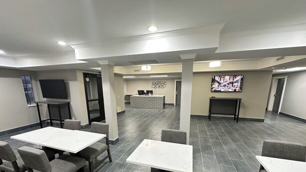 A hotel lobby with multiple seating areas, a reception desk, and a television screen. - Quality Inn Carlin (Carlin)