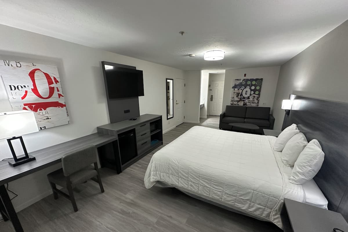 A hotel room with a bed, desk, TV, and a couch.