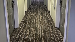 A hotel hallway with carpeted floors, doors on both sides, and a light fixture on the ceiling. - Quality Inn Carlin (Carlin)
