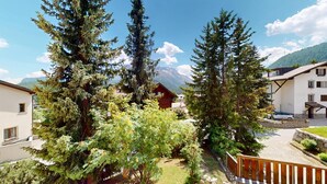 Um refúgio de montanha com vista para picos nevados, rodeado por altas árvores perenes e um jardim bem cuidado.