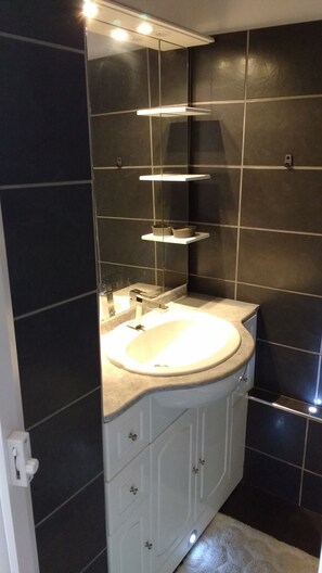 A bathroom with a white sink, dark tiled walls, and a mirror above the sink. - 58m2 flat in ST Raphael-600 metres from the beach and train station-free parking (Saint-Raphaël)