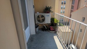 A balcony with an air conditioning unit, potted plants, and a view of neighboring buildings. - 58m2 flat in ST Raphael-600 metres from the beach and train station-free parking (Saint-Raphaël)