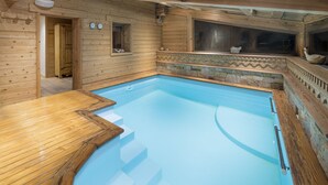 Une cabane en bois dotée d’une piscine, d’une terrasse en bois et d’éléments décoratifs en pierre.