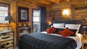 Une pièce aménagée comme un chalet en bois, avec un lit, une commode, une lampe et un cadre photo fixé au mur.