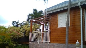 A wooden house with a balcony, a stone pathway, and a garden with various plants. - DISCOVER MY CHARMING BUNGALOW WITH POOL (Le Gosier)