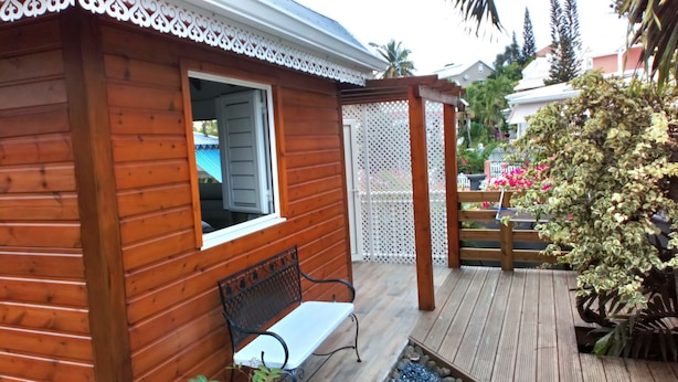 A wooden cabin with a bench and a lattice fence. - DISCOVER MY CHARMING BUNGALOW WITH POOL (Le Gosier)