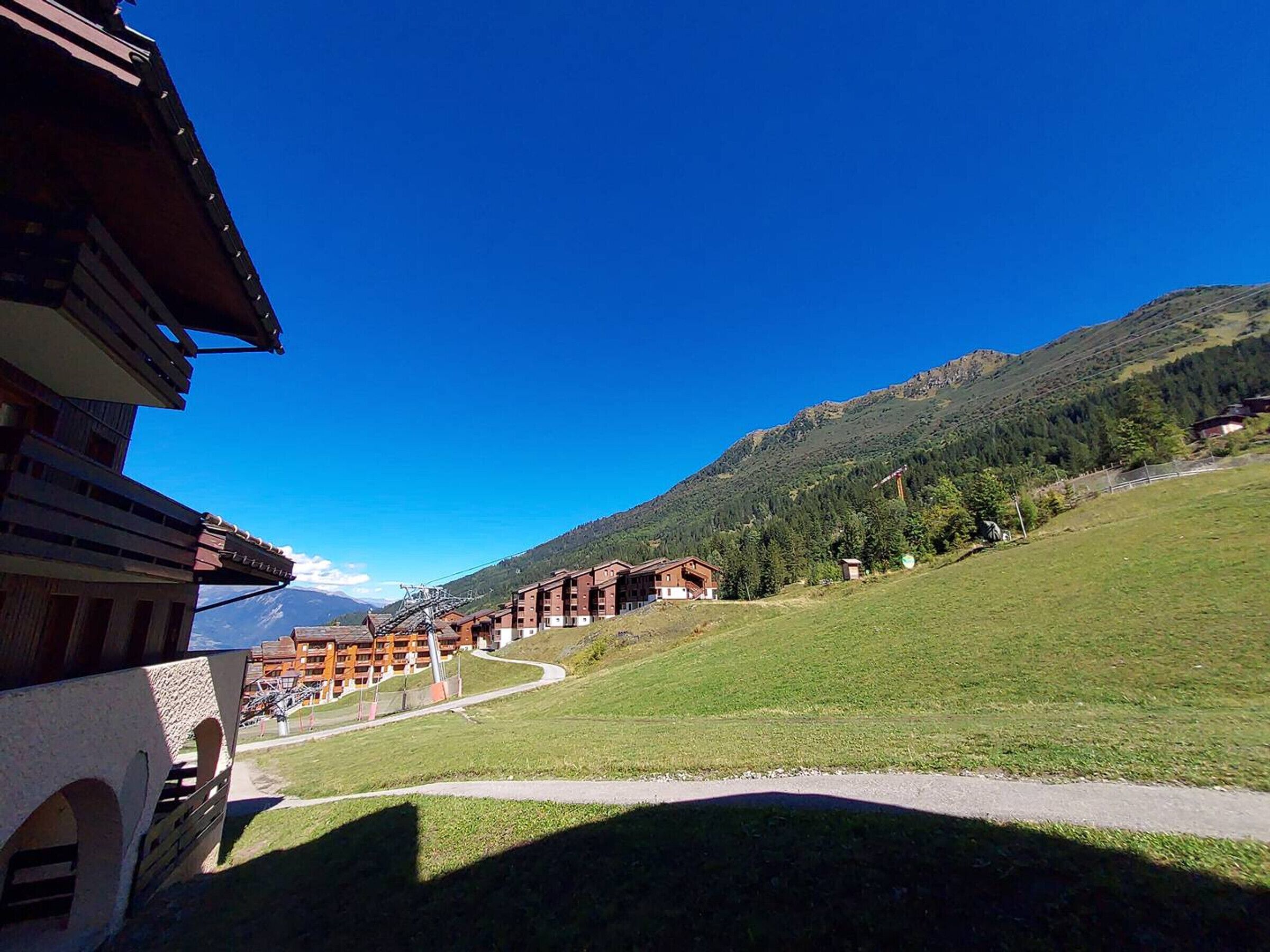 Ein Hotel im traditionellen alpinen Baustil, mit einem Innenhof und einem Weg, der zu einer Bergblick führt.