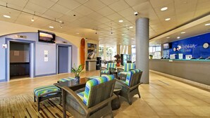 Un hall d'entrée avec des sièges, un comptoir de réception et un mur bleu orné d'une enseigne indiquant « AQUA ALOHA SURE ».