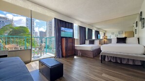 Une chambre d’hôtel avec un balcon, une télévision, un lit, un canapé et une petite table.