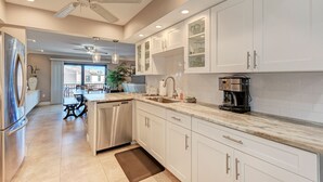 A modern kitchen with white cabinets, stainless steel appliances, and a granite countertop. - Spacious beachfront Penthouse 3 bed/3 bath suite, Stunning Gulf views! (Siesta Key)