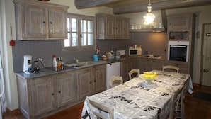 A kitchen with wooden cabinets, a dining table with a floral tablecloth, and a microwave.