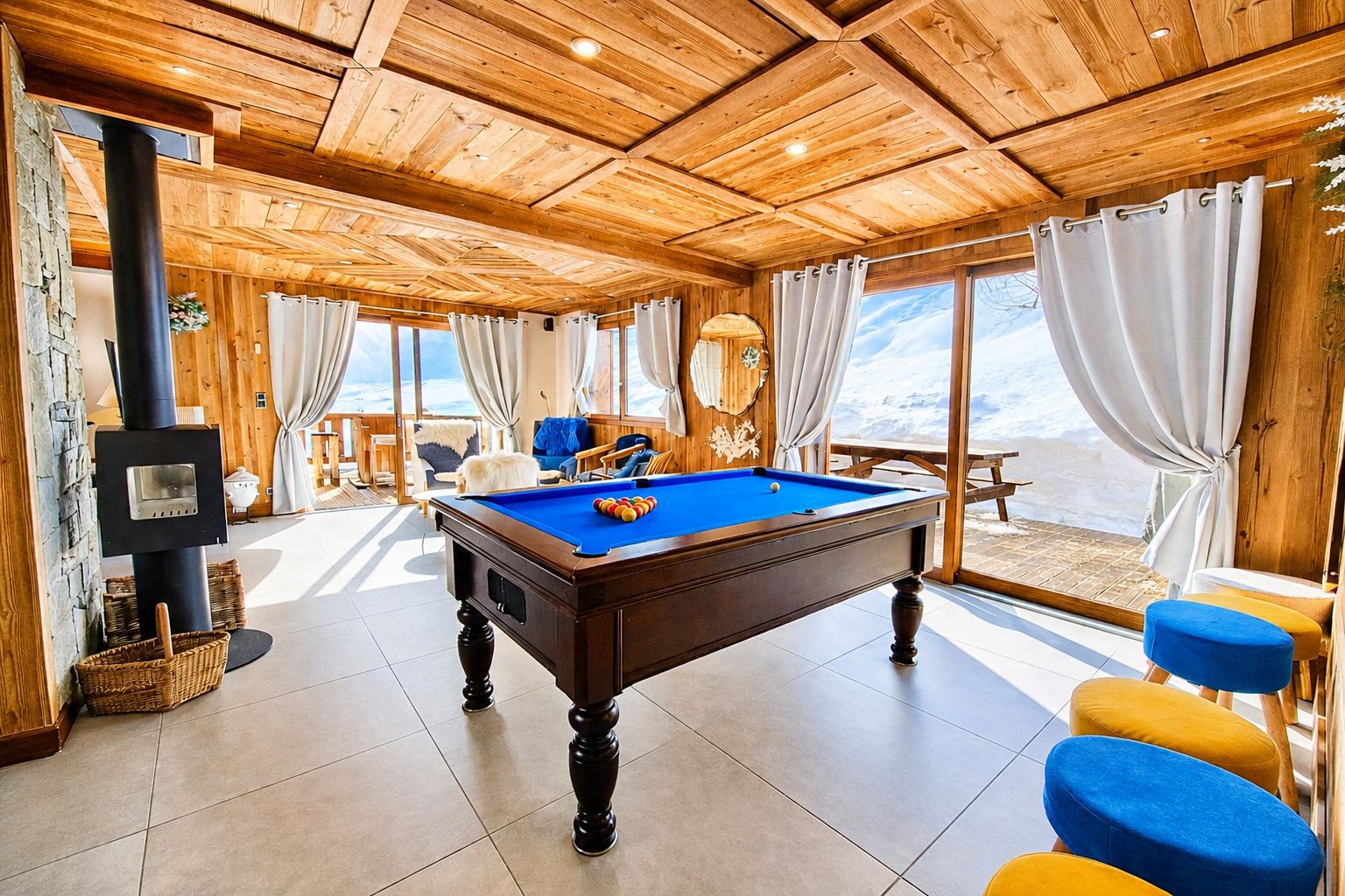A pool table in a room with wooden ceiling and large windows.