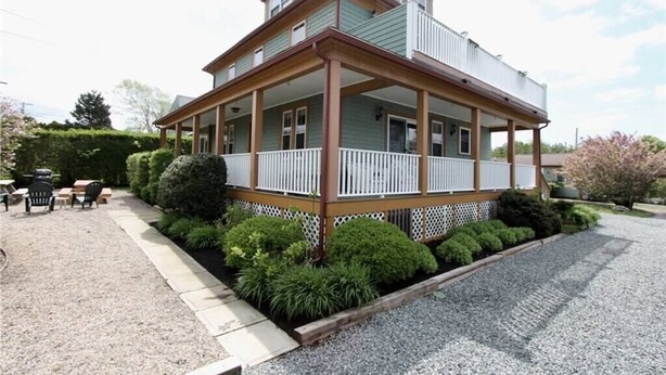 Ein zweistöckiges Haus mit einer Veranda und einer kleinen Terrasse.