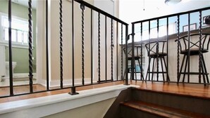 Eine Treppe mit schwarzer Geländer führt zu einem Essbereich mit Holzsesseln.