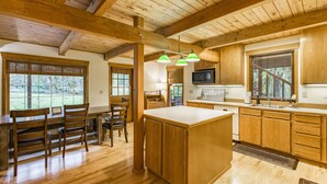 A spacious kitchen with wooden cabinets, a large island, and a dining area with chairs. - 4,000 sqft Mt. Baker Ski Lodge, sleeps 21, walk to town, hot tub, fiber internet (Glacier)