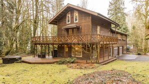 A wooden cabin with a deck, surrounded by trees. - 4,000 sqft Mt. Baker Ski Lodge, sleeps 21, walk to town, hot tub, fiber internet (Glacier)