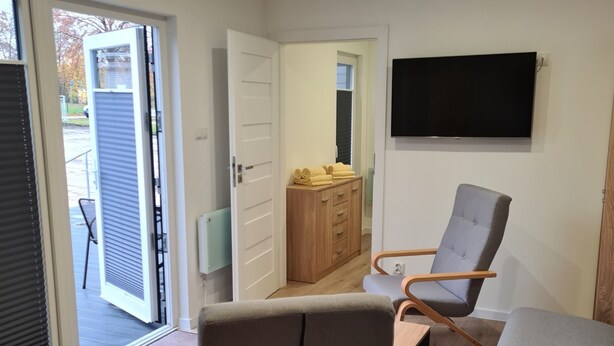 Una sala moderna con un sofá, sillas, un televisor y un mueble de madera.